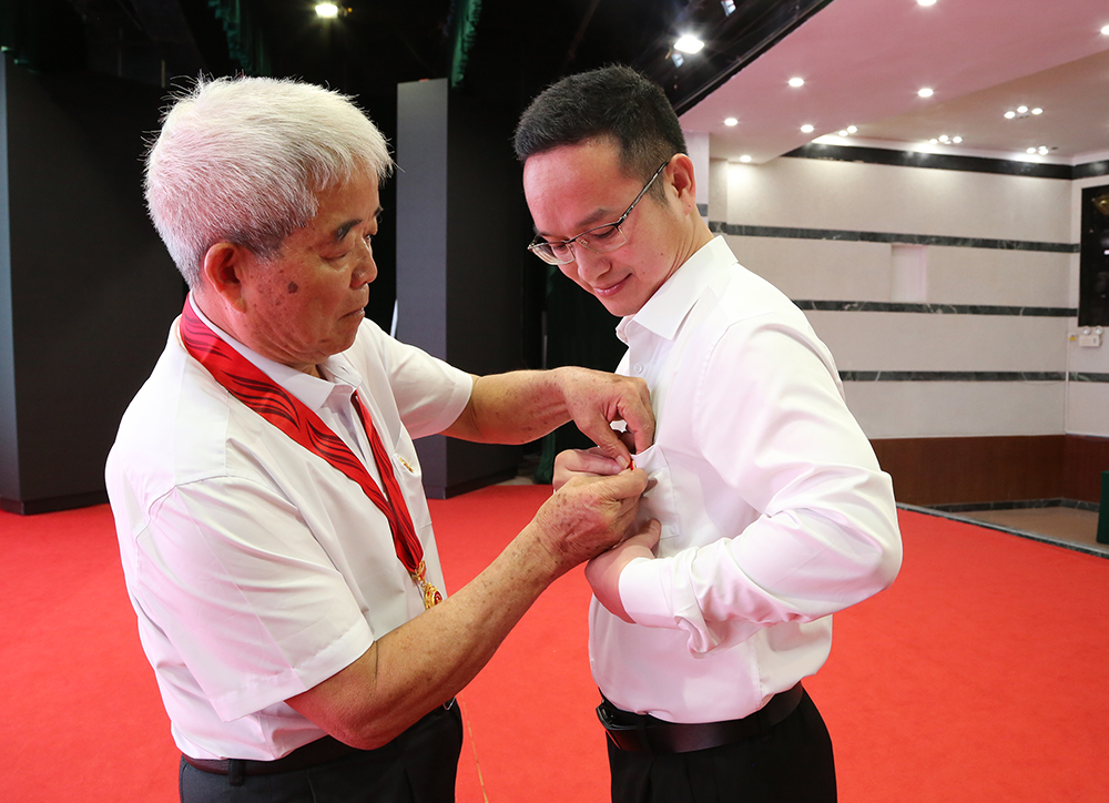 “光荣在党50年”的老党员给新任党支部书记代表佩戴党徽0.jpg